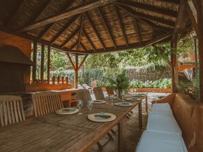 A wooden dining area with a thatched roof, surrounded by greenery and stone walls. - Country House in Gran Canaria With Private Pool (Vega de San Mateo)