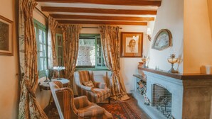 Une pièce de style traditionnel, dotée d’une cheminée, de deux fauteuils, d’un tapis à motifs et de rideaux.