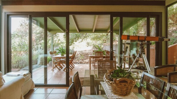 Une terrasse ensoleillée avec une table à manger, des chaises et un canapé.