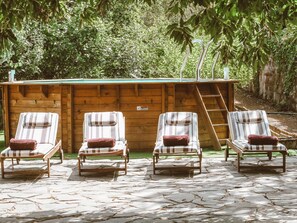 A wooden cabin with a pool area, four lounge chairs with striped cushions, and a stone patio. - Country House in Gran Canaria With Private Pool (Vega de San Mateo)