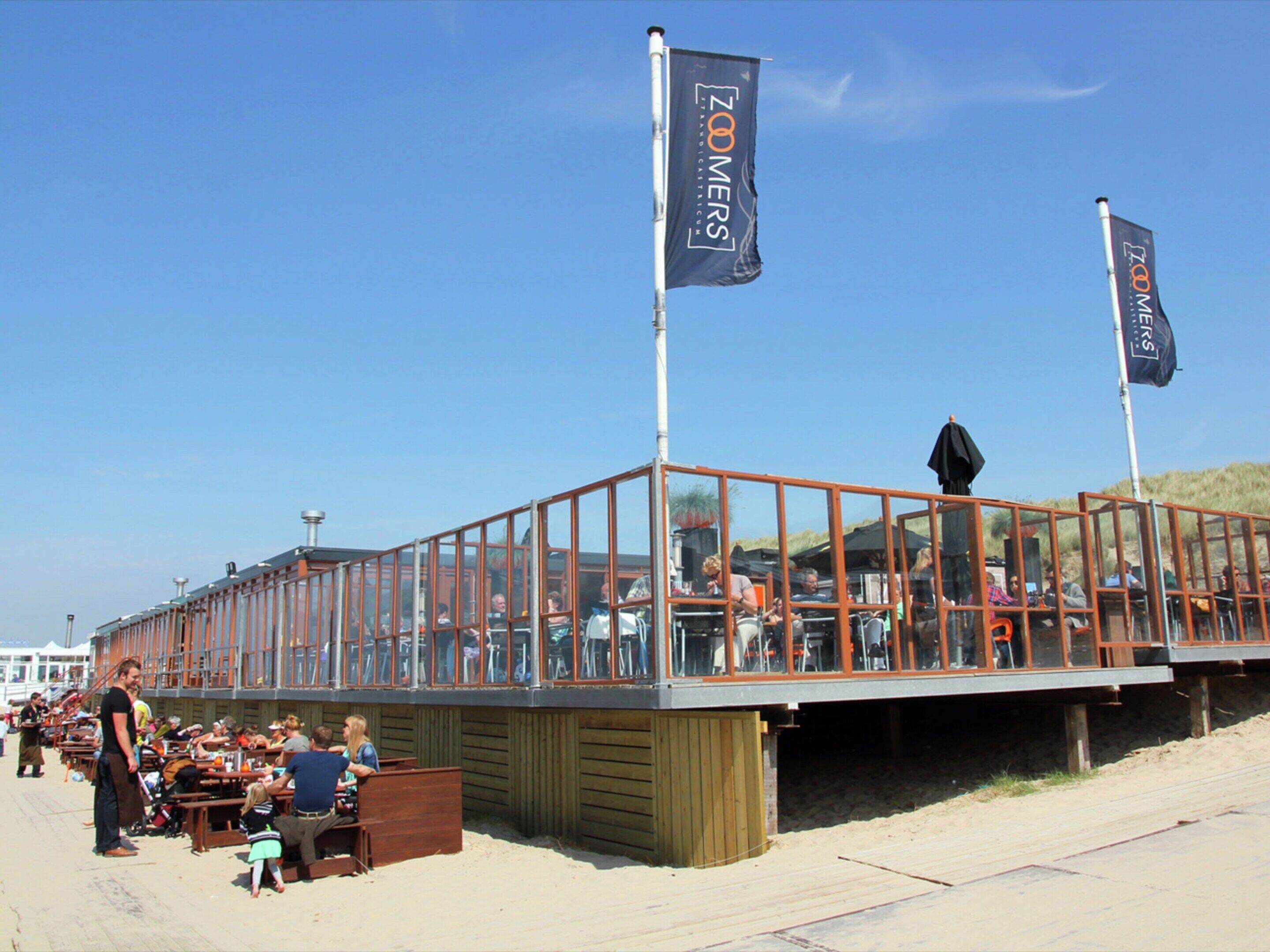A beachside restaurant with outdoor seating and a view of the ocean.
