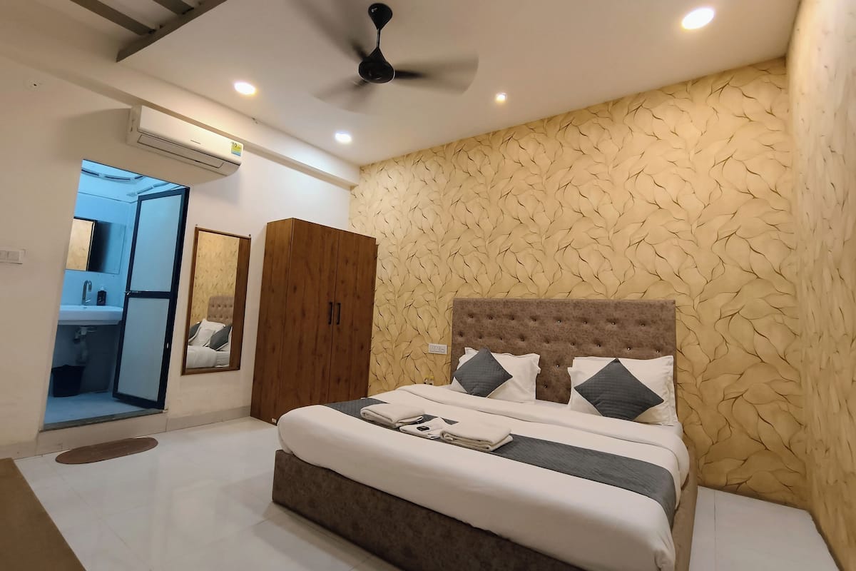 A bedroom with a bed, a wardrobe, a ceiling fan, and a bathroom visible through an open door.