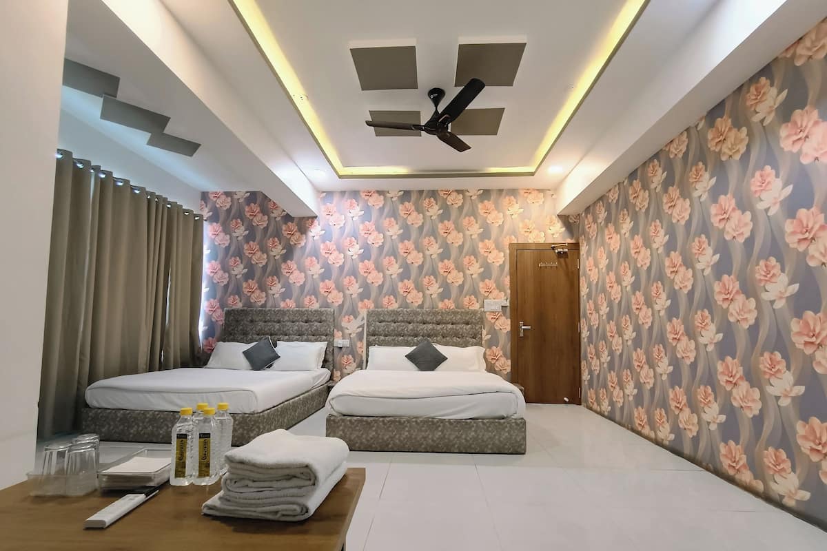 A bedroom with two beds, a ceiling fan, and floral wallpaper.