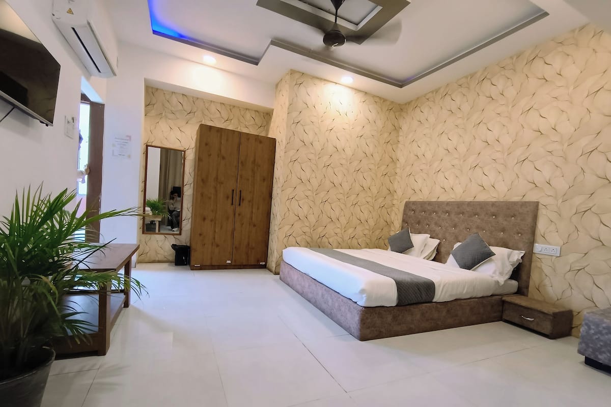 A modern bedroom with a large bed, a wardrobe, and a mirror.
