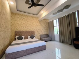 A modern hotel room with a large bed, a chair, and a TV.
