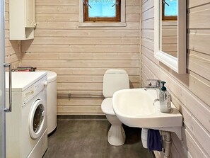 A compact bathroom with a washing machine, toilet, and sink.
