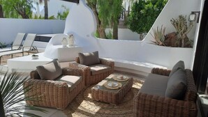 An outdoor patio with wicker furniture, a round table, and a decorative rug. - Bungalow Villa del Sol (Pajara)