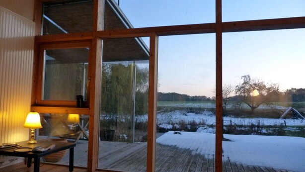 A room with a large sliding glass door leading to a deck with a snowy landscape view. - Toad 5 on the Soederbring (Waddeweitz)