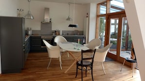 A modern kitchen with a dining area, wooden flooring, and large windows. - Toad 5 on the Soederbring (Waddeweitz)