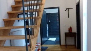 A modern interior with a wooden staircase, a hallway leading to a door, and a small table with a bottle. - Toad 5 on the Soederbring (Waddeweitz)