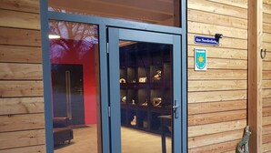 A wooden building with a glass door entrance, a sign reading "Am Soederbring," and a coat hanging on the wall. - Toad 5 on the Soederbring (Waddeweitz)