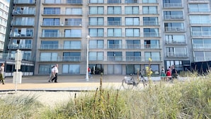 Edifício residencial de vários andares com varandas, uma passarela para pedestres e uma bicicleta estacionada em primeiro plano.