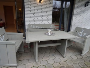 An outdoor patio with a white table and two grey benches. - Holiday Apartment Itzke 2 (Kappeln)
