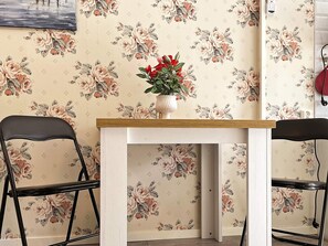 A dining area with floral wallpaper, a white table, and two black chairs. - 4 Person Holiday Home in Gusum (Valdemarsvik)