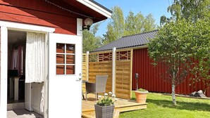 Eine Holzterrasse mit einem Korbstuhl, einem Blumentopf und einem kleinen Tisch.