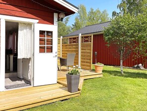 A wooden deck with a wicker chair, a potted plant, and a small table. - 4 Person Holiday Home in Gusum (Valdemarsvik)