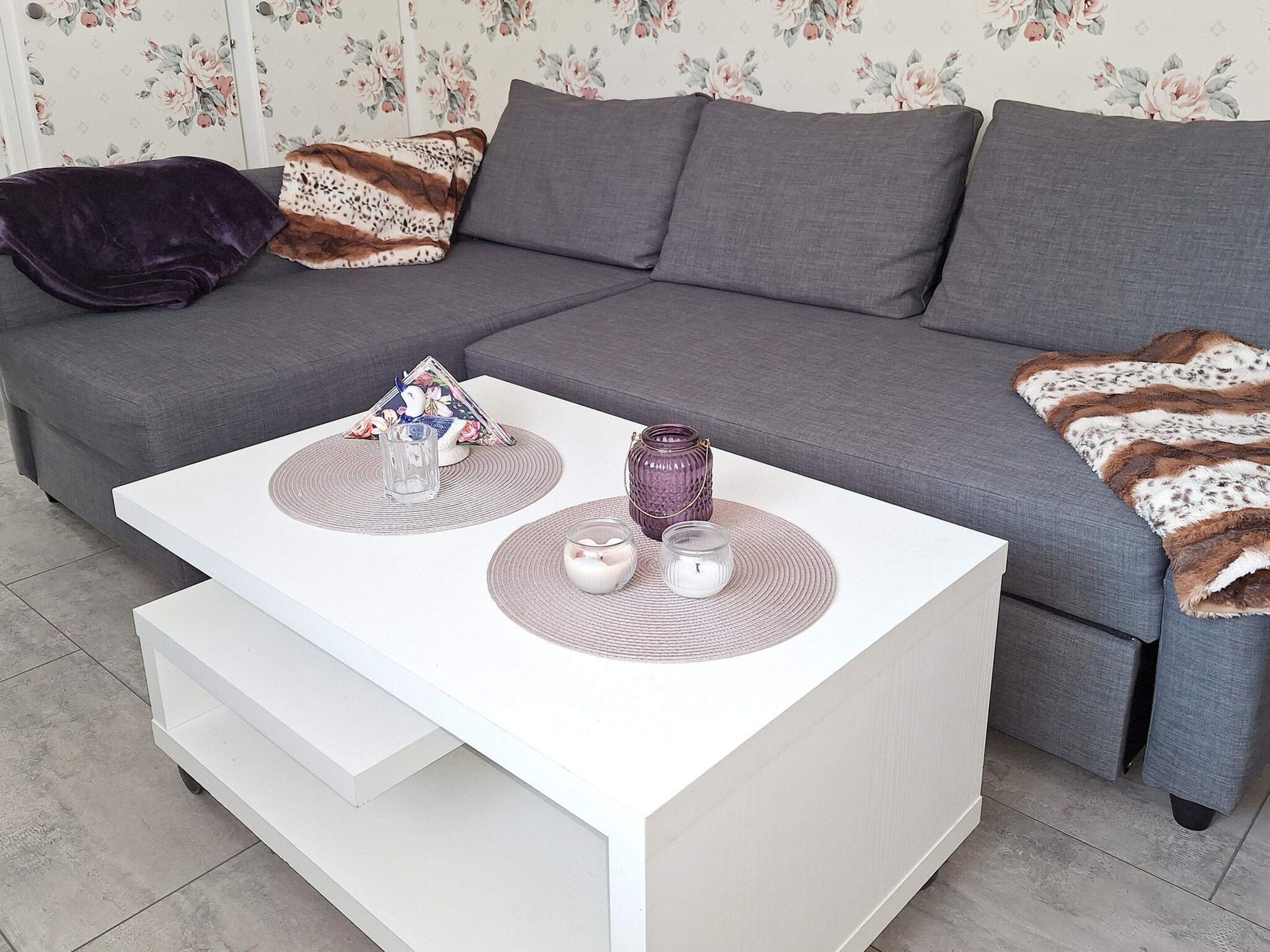 A modern living room with a grey sofa, a white coffee table, and decorative items.