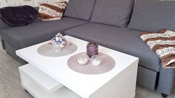A modern living room with a grey sofa, a white coffee table, and decorative items.