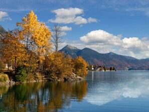 A serene lakeside view with autumn foliage, a mountain backdrop, and a clear sky. - Lovely Apartment in Lenggries (Lenggries)