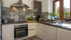 A modern kitchen with a built-in oven, stainless steel range hood, and patterned backsplash. - Villa Casa Ida Comfortable Holiday Residence (Groznjan)