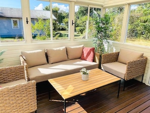 A covered outdoor seating area with a sofa and chairs, a wooden table, and a potted plant. - 4 Star Holiday Home in Solvesborg (Sölvesborg)