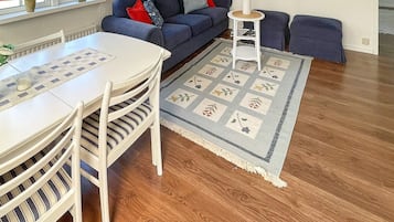 A living room with a white table, striped chairs, a blue sofa, and a patterned rug.