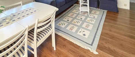 A living room with a white table, striped chairs, a blue sofa, and a patterned rug.
