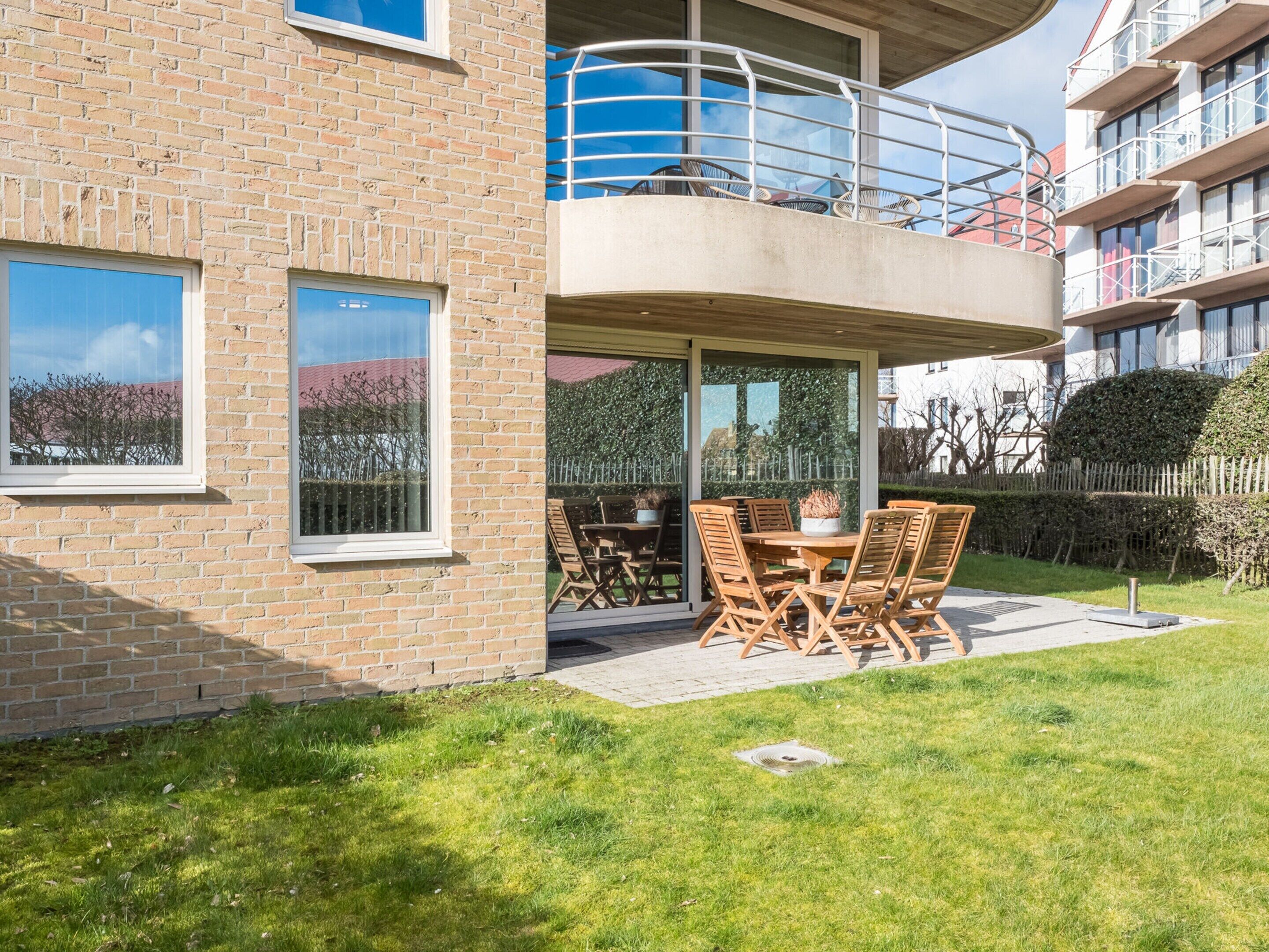 Eine moderne Wohnung mit Balkon, Sitzgelegenheit im Freien und Blick auf benachbarte Gebäude.