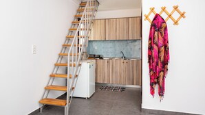 A kitchen with wooden cabinets, a white refrigerator, and a sink. - Marina's studios (Santorini)