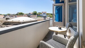 A balcony with a table and chairs, a view of the surrounding area, and a door with a blue curtain. - Zoutelande Retreat by Sea (Zoutelande)