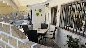 A patio area with a table and chairs, a potted plant, and a stone wall. - Apartment The Little La Perla (Arona)