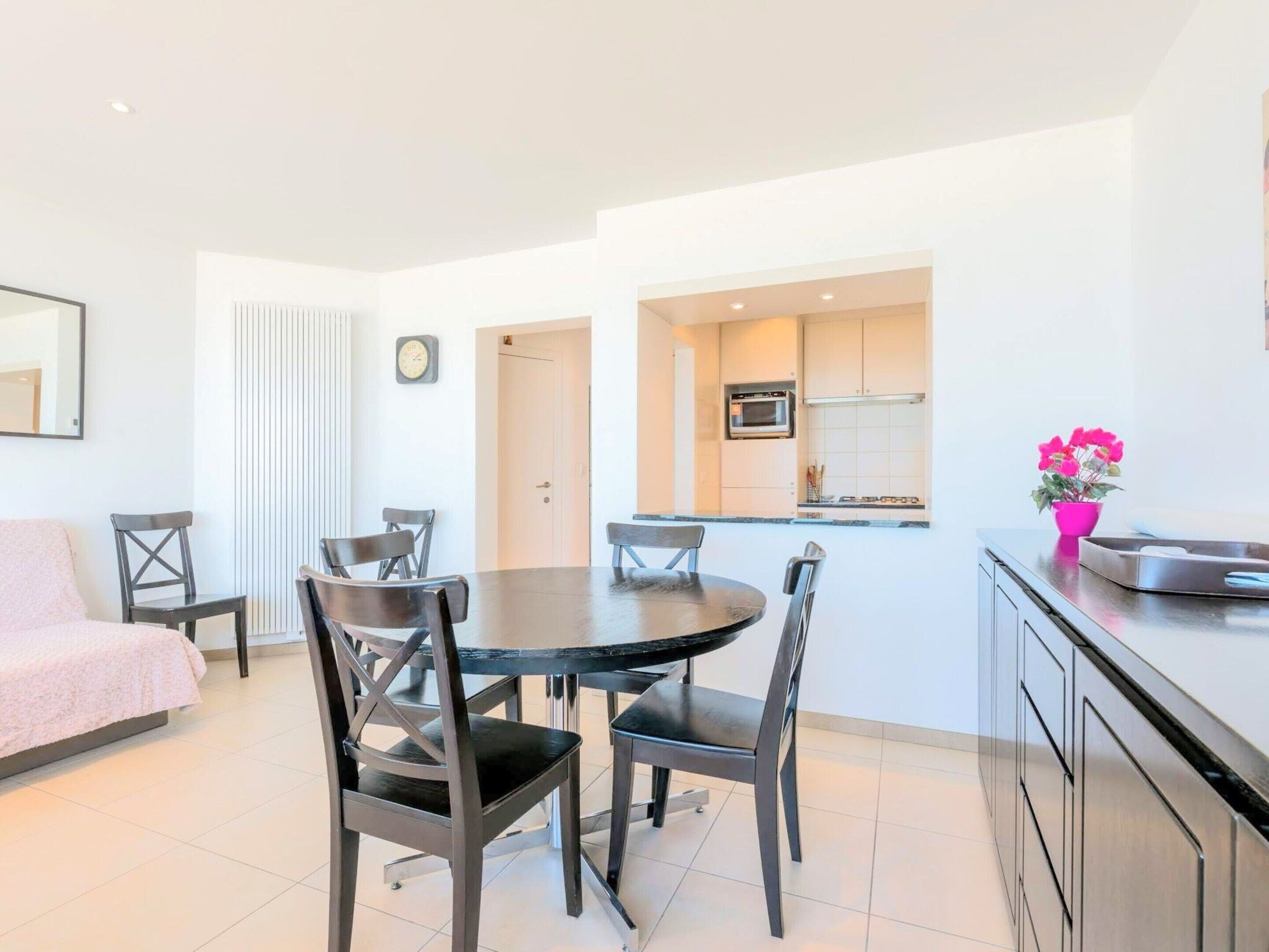 A modern apartment with a dining area, kitchen, and a bed.