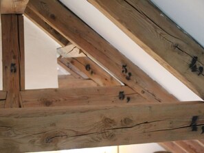 Estructura de techo de madera con vigas visibles y un panel blanco.