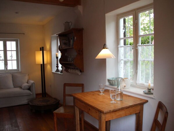 A cozy room with a wooden table, chairs, a lamp, a bookshelf, and a window with a view of greenery. - Pleasant Apartment in Diessen (Dießen am Ammersee)