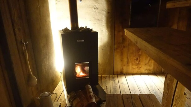 Une pièce chaleureuse avec un poêle à bois, un plancher en bois et un banc.