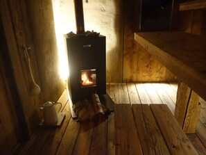 A cozy room with a wood-burning stove, wooden flooring, and a bench. - Pleasant Apartment in Diessen (Dießen am Ammersee)