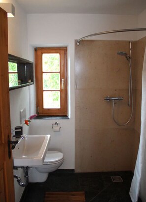 Un baño con ducha, inodoro, lavamanos y ventana.