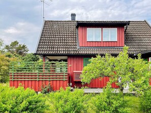 A red house with a tiled roof and a green fence.