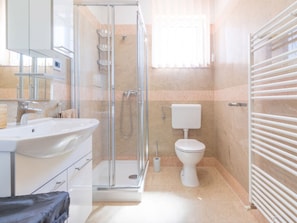 Ein modernes Badezimmer mit Duschkabine aus Glas, einem weißen Waschbecken und einer Toilette.