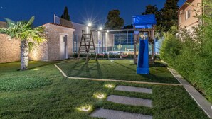 A well-lit outdoor area with a play structure, a slide, and a stone building. - Istra Kamen Comfortable Holiday Residence (Liznjan)