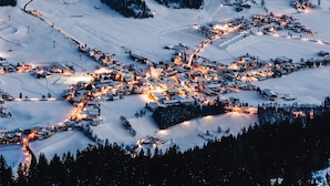 A snow-covered village with illuminated buildings and winding roads. - Luxury Apartment, Alpenrosenbahn Within Walking Distance (Westendorf)