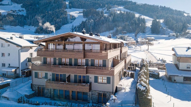 A multi-story hotel with a wooden facade, large windows, and a ski slope in the background. - Luxury Apartment, Alpenrosenbahn Within Walking Distance (Westendorf)