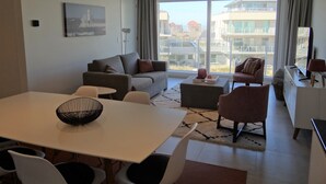 A modern living room with a sofa, armchairs, a dining table, and a TV. - Nieuwpoort Beach Getaway (Koksijde)