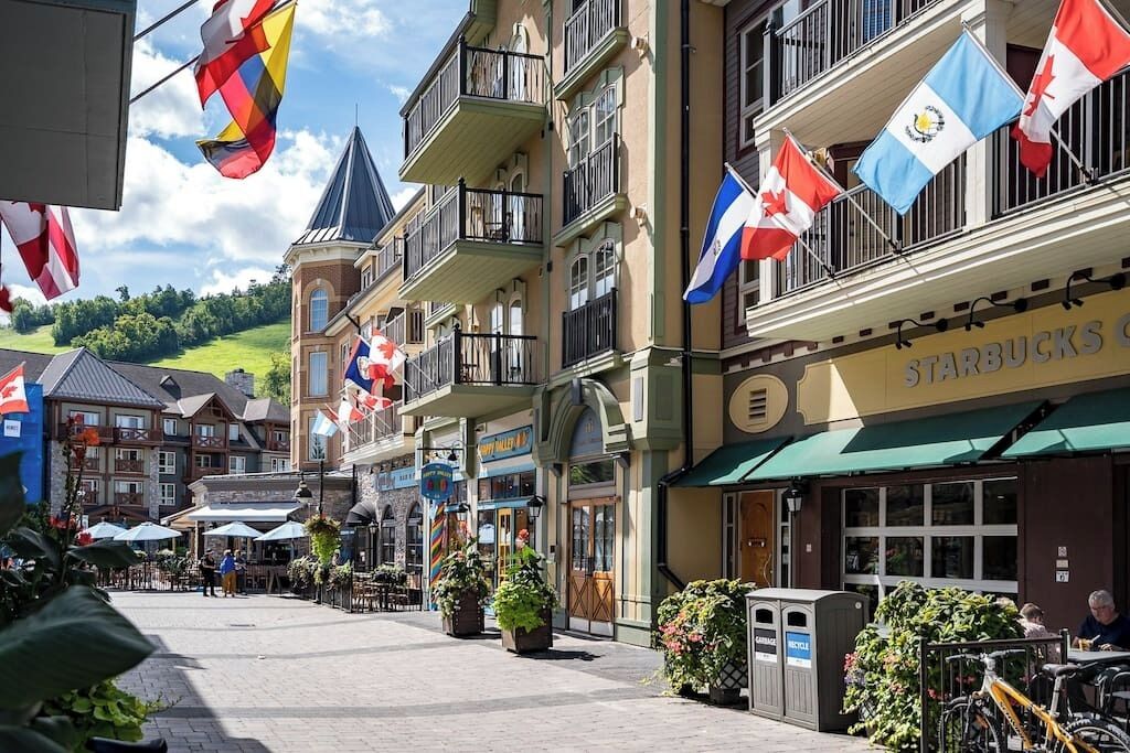 Een straat met gebouwen, terrasjes en vlaggen.