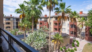 Un edificio residencial con varios balcones, palmeras y un jardín bien cuidado.
