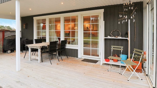 A covered patio area with a table and chairs, a grill, and a sliding glass door leading to an interior space. - 5 Person Holiday Home in Laeso (Læsø)