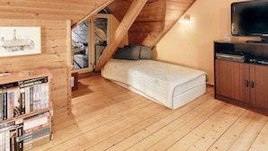 A cozy attic bedroom with a sloped ceiling, a single bed, a wooden bookshelf, and a television. - 5 Person Holiday Home in Laeso (Læsø)