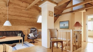 A cozy room with a wooden ceiling, a brown leather sofa, a wooden dining table, and a wicker chair. - 5 Person Holiday Home in Laeso (Læsø)