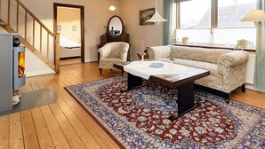 A cozy living room with a sofa, a coffee table, a fireplace, and a large window with curtains. - 5 Person Holiday Home in Laeso (Læsø)