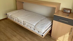 A compact room with a foldable bed, a small wooden cabinet, and a radio. - Sonnenhof Holiday Apartment 4 (Enkirch)